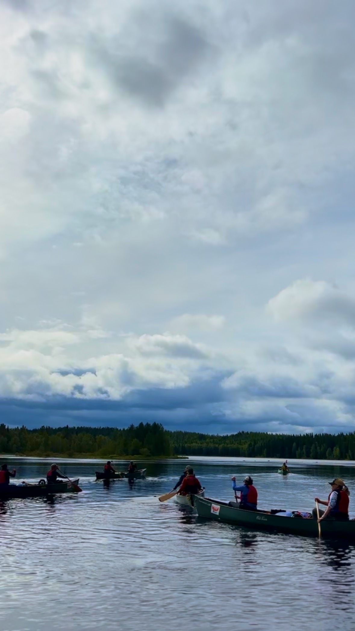 Group paddling canoe on a lake with dramatic sky
